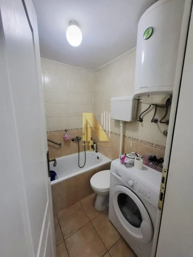 Manje kupatilo sa kadom, wc šoljom i veš mašinom.
