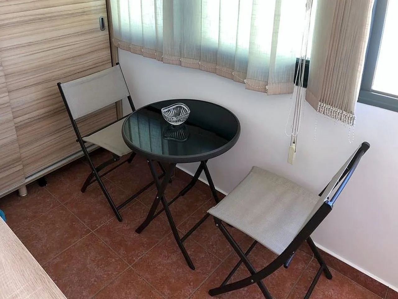 Small covered terrace with a round table and two chairs.