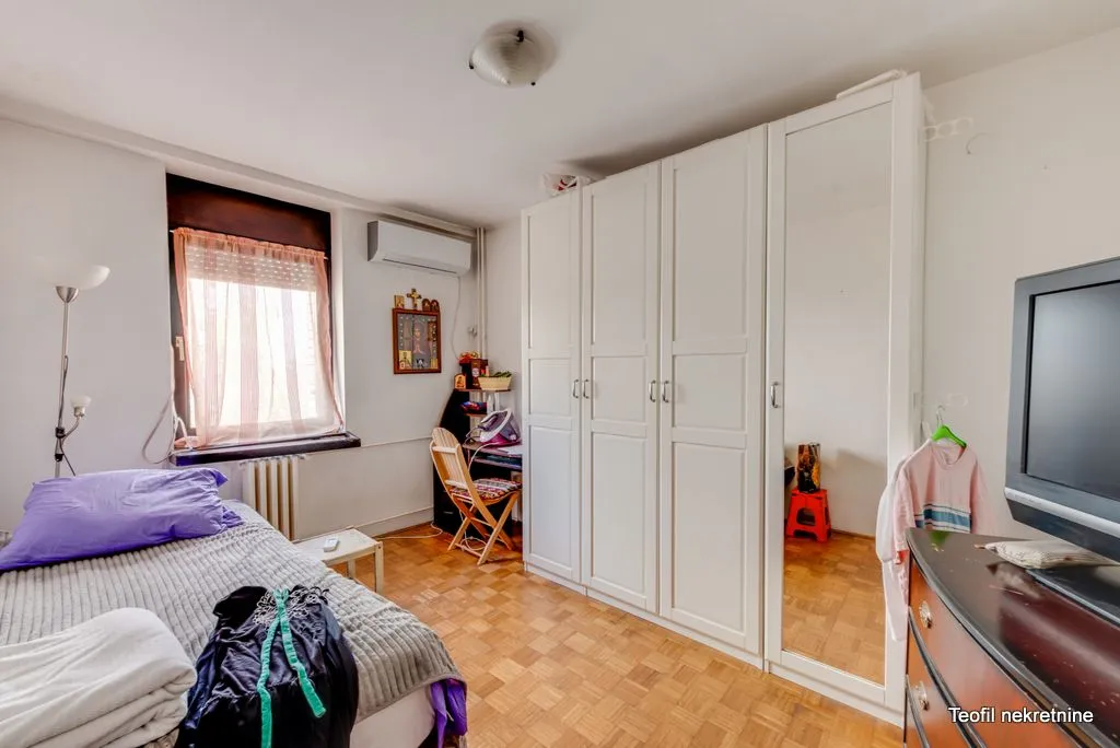 Bedroom with a bed, large white wardrobe, and a television.