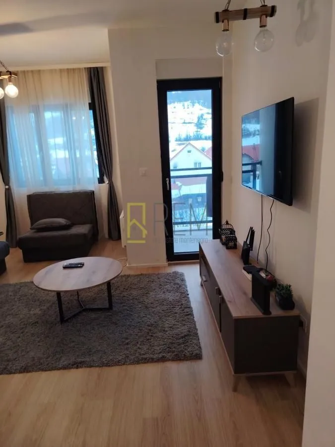 Dnevni boravak sa garniturom, TV-om i izlazom na terasu.