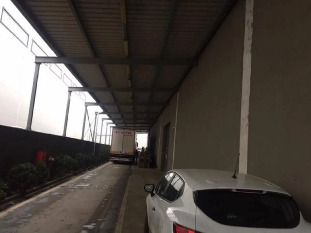 Covered driveway and parking area in front of the building with a parked car and truck.
