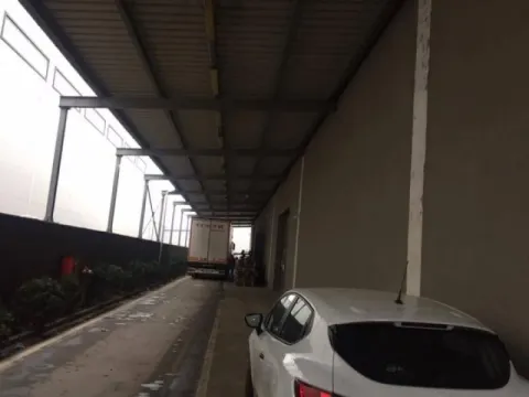 Covered driveway and parking area in front of the building with a parked car and truck. - image 3