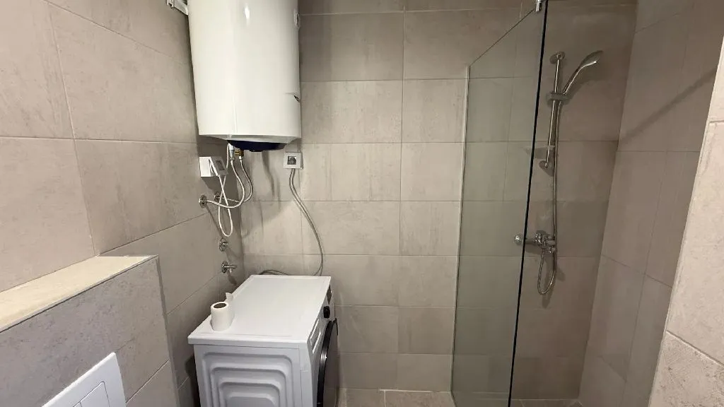 Moderno opremljeno kupatilo sa tuš kabinom, bojlerom i veš mašinom.