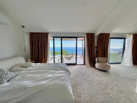 Spacious bedroom with a double bed, carpet, and large glass surfaces with a sea view. - image 10