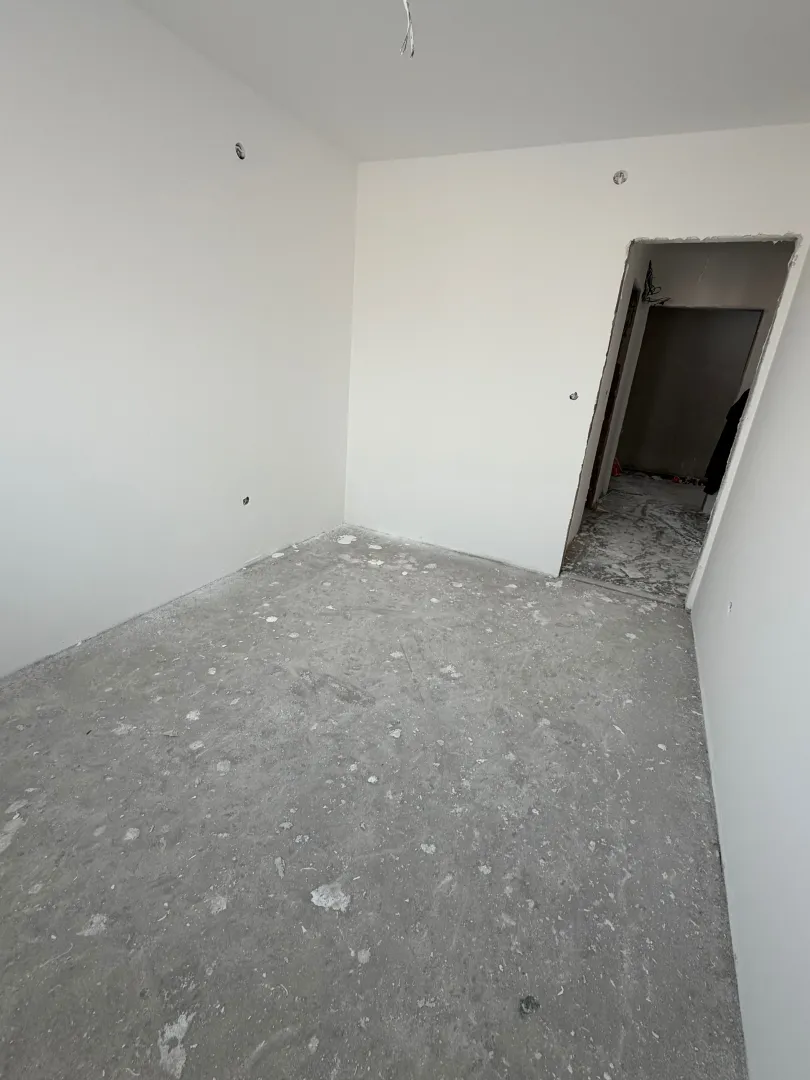 Prazna neuređena prostorija u stanu u izgradnji sa bijelim zidovima.