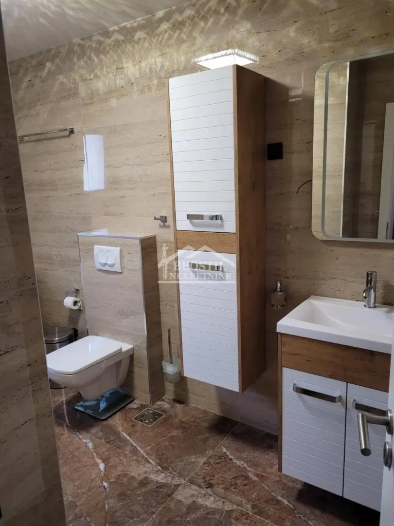 Opremljeno kupatilo sa umivaonikom, WC šoljom i zidnim ormarićem.