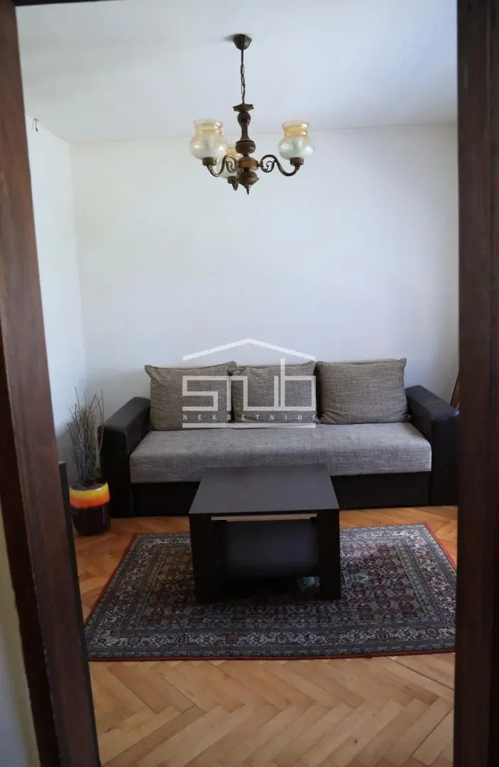 Living room with a sofa, coffee table, and rug, viewed through the doorway.