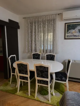 Dining area with a white table and six chairs in an apartment. - image 3