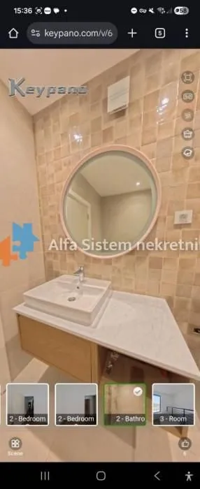 Kupatilo sa umivaonikom i okruglim ogledalom.