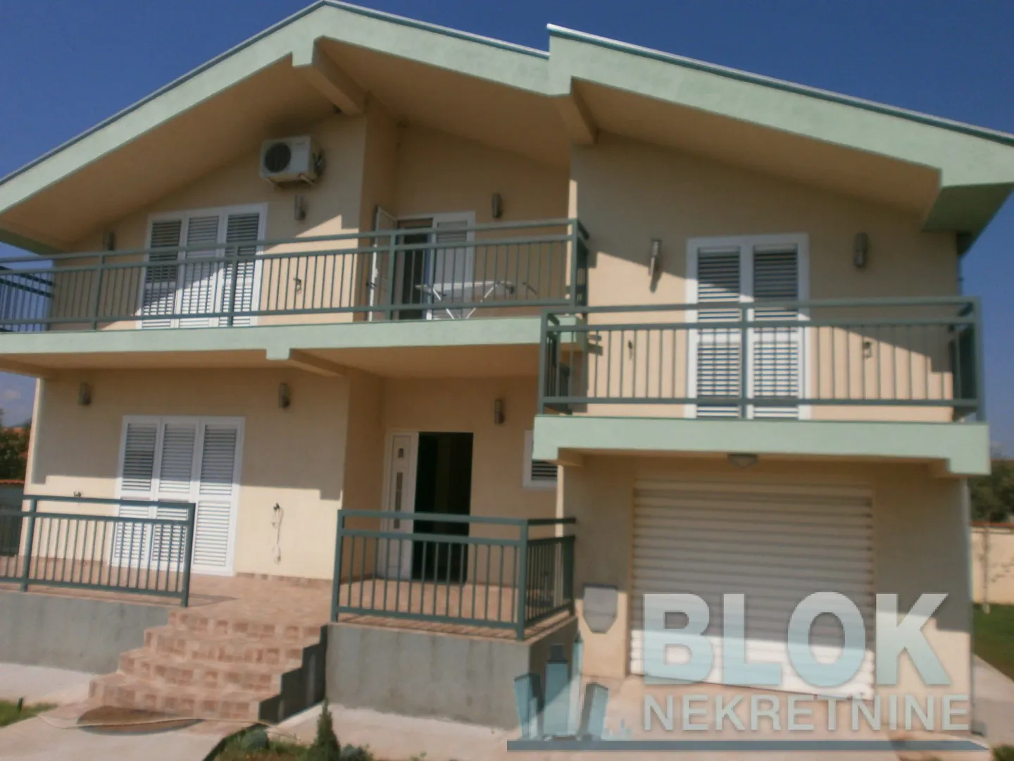 Front view of a two-story house with balconies and a garage.