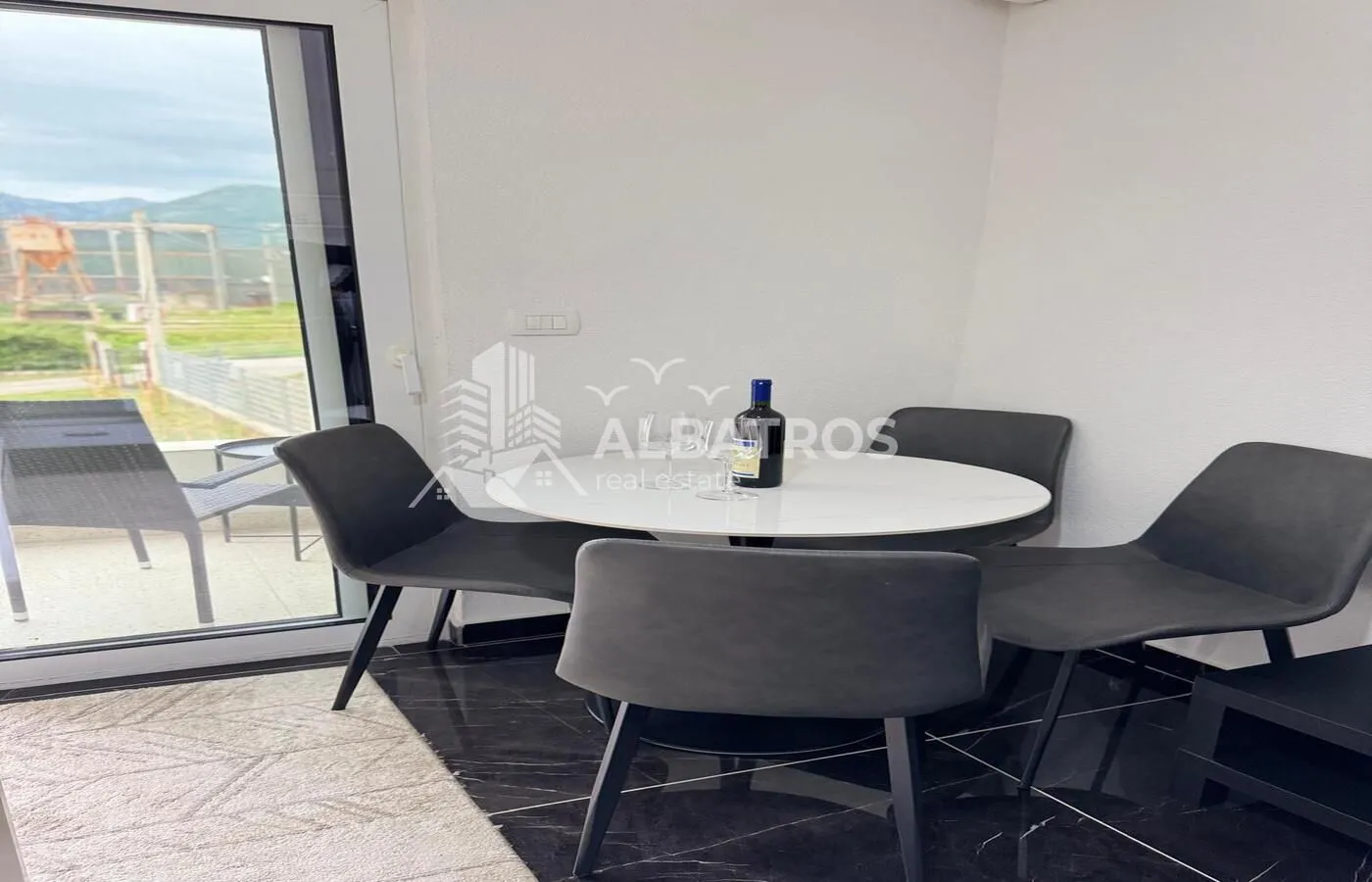 Dining table with four chairs and a view of the terrace.