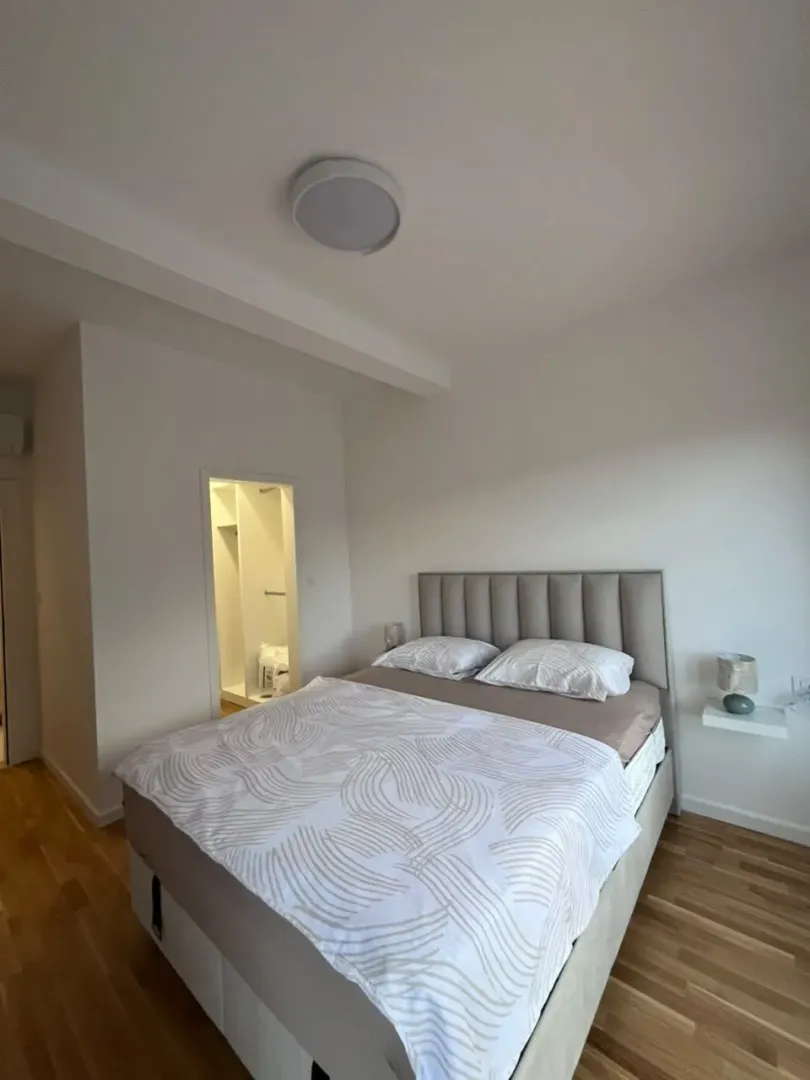 Svijetla spavaća soba sa bračnim krevetom i garderoberom u pozadini.