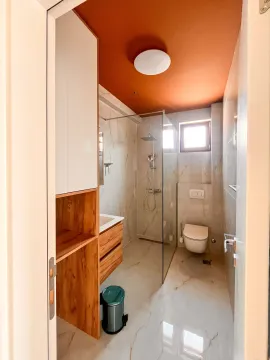 Moderno opremljeno kupatilo sa tuš kabinom i narandžastim plafonom. - image 13