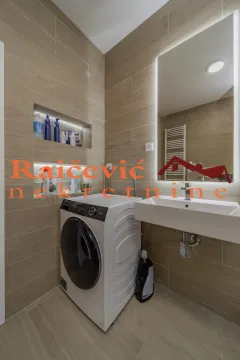 Kupatilo obloženo keramičkim pločicama sa umivaonikom, ogledalom i veš mašinom. - image 18