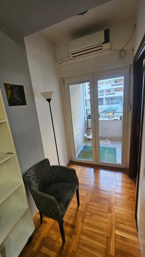 Manji svijetli dnevni boravak sa foteljom i izlazom na terasu.