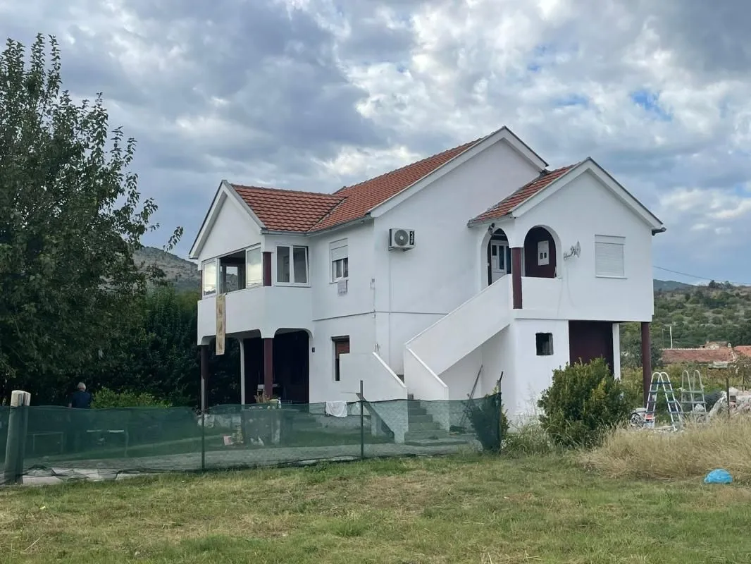 View of a two-story house with a white facade and yard.