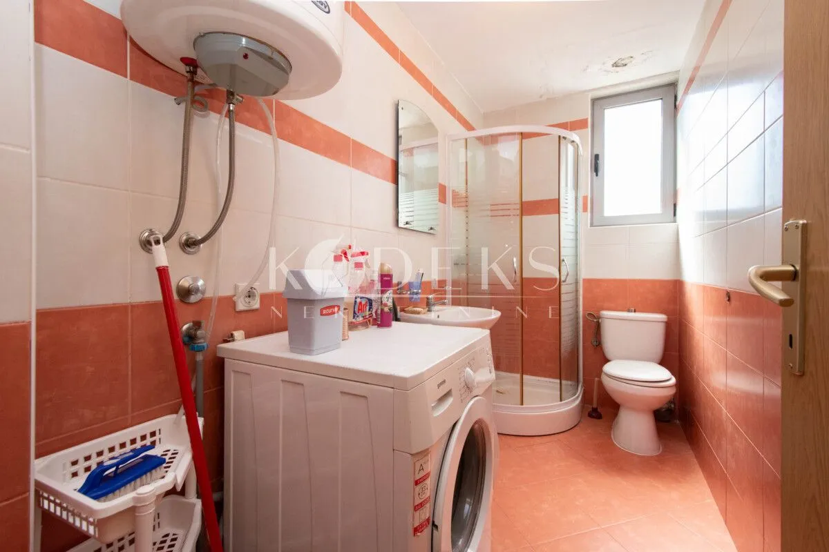 Kupatilo opremljeno tuš kabinom, sanitarijama i veš mašinom.