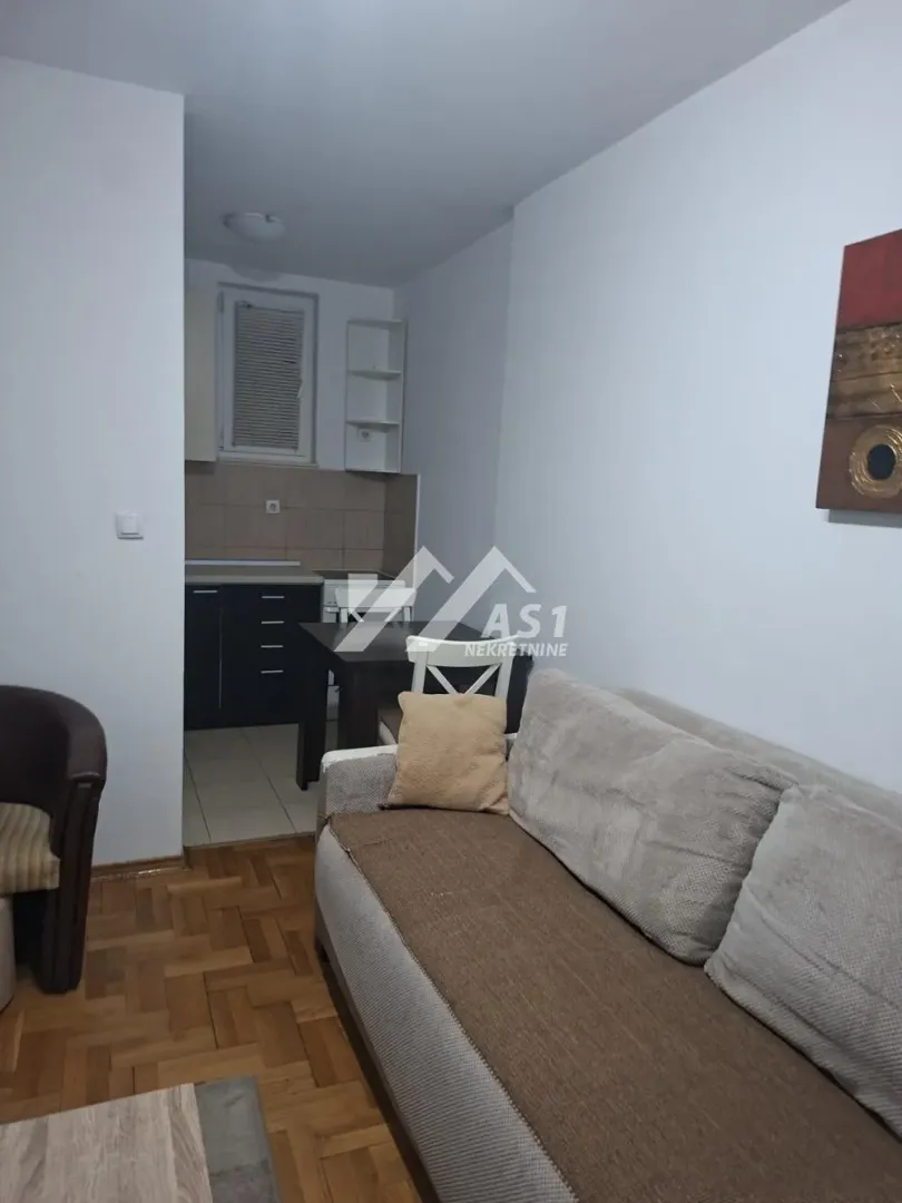 Dnevni boravak sa garniturom i pogledom na kuhinju u pozadini.