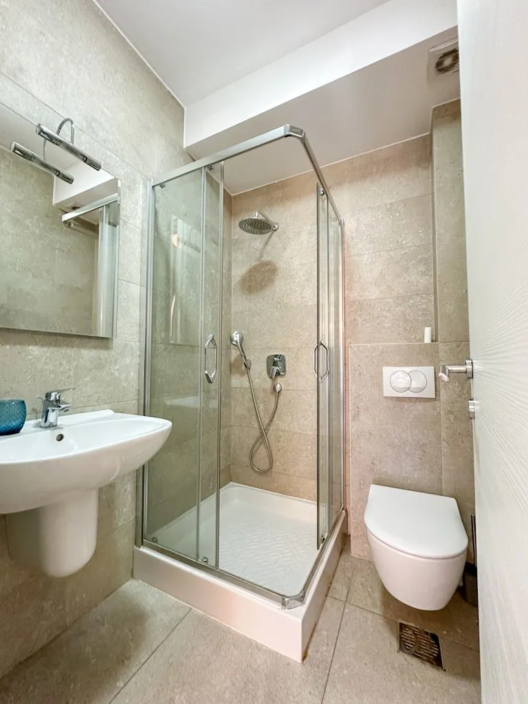 Modern bathroom with a shower cabin, washbasin, and toilet.