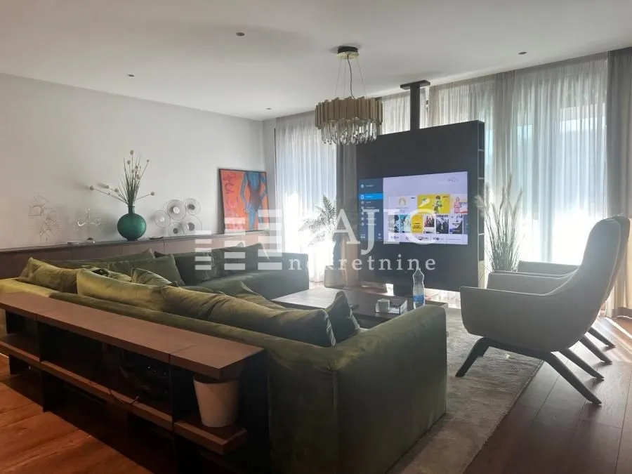 Spacious living room with a sofa, armchair, and TV.