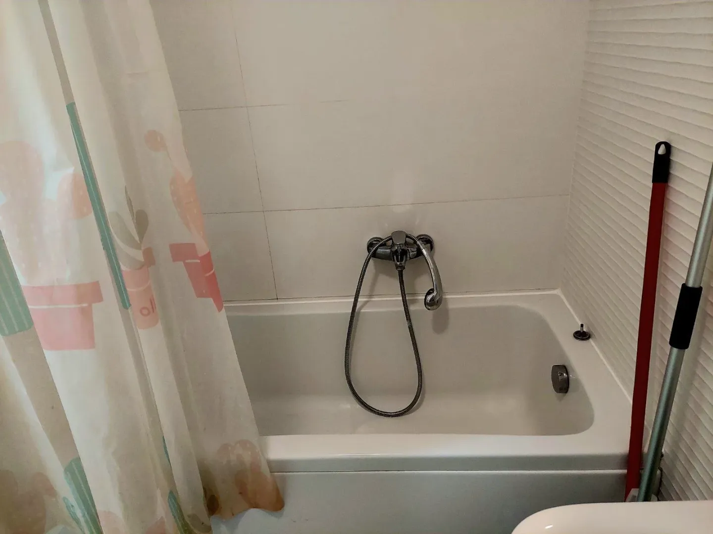 Manje kupatilo sa kadom i tuš zavjesom.