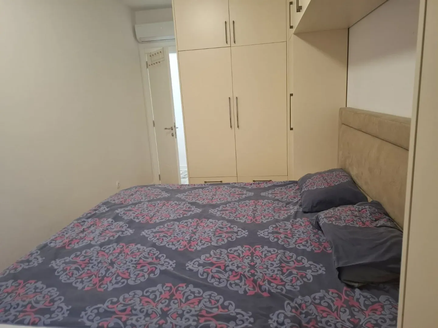 Namještena spavaća soba sa bračnim krevetom i ugradnim ormarom.