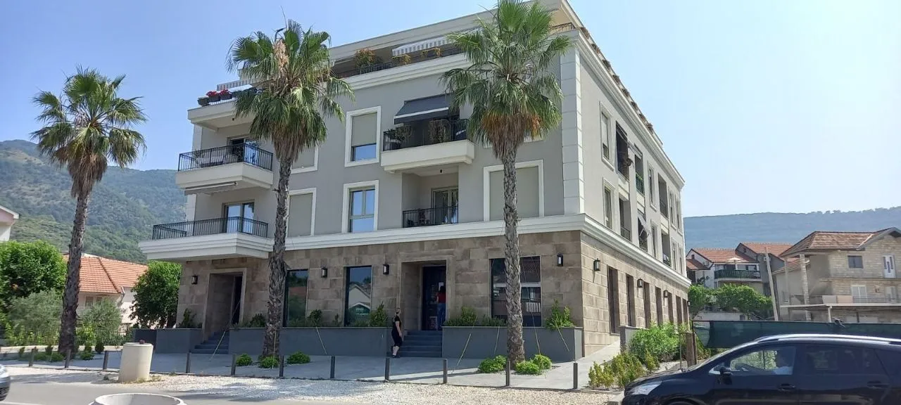 Exterior of a modern residential building with palm trees in front.