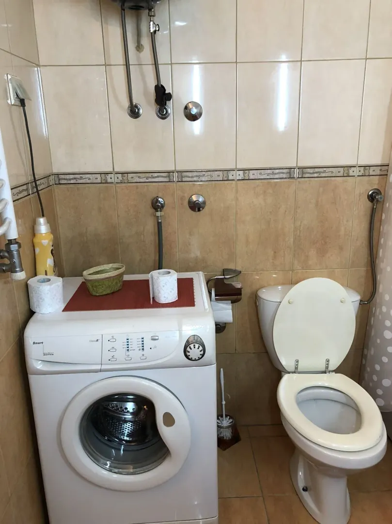 A simple bathroom featuring a washing machine and a toilet.