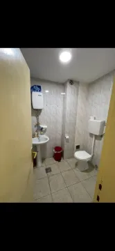 Smaller bathroom with tiling, washbasin, and toilet. - image 9