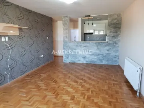 Dnevna soba sa parketom i pogledom na kuhinjski šank obložen dekorativnim kamenom. - image 4
