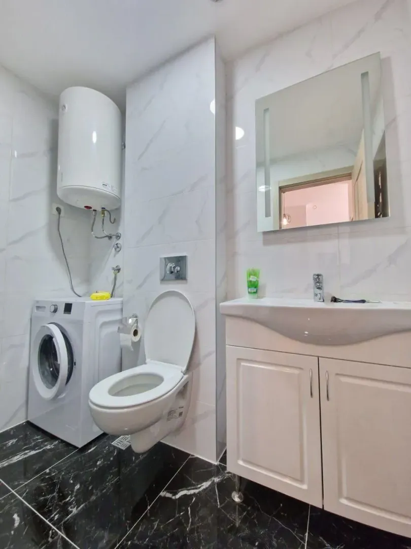 Moderne kupatilo sa umivaonikom, WC šoljom, veš mašinom i bojlerom.