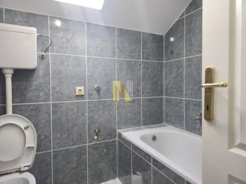 Manje kupatilo obloženo pločicama sa kadom i toaletom. - image 5