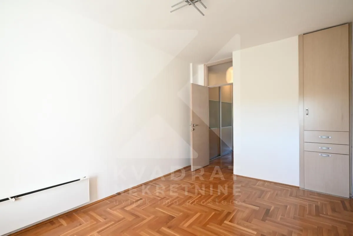 Empty room with hardwood parquet flooring and a built-in closet.