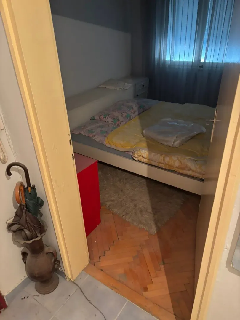 Pogled iz hodnika na spavaću sobu sa krevetom i parketom.