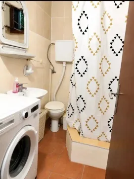 Small bathroom with a shower cabin, washbasin, and washing machine. - image 4