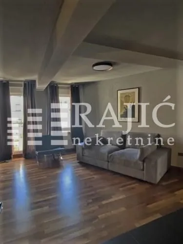 Spacious living room with a sofa and wooden flooring.