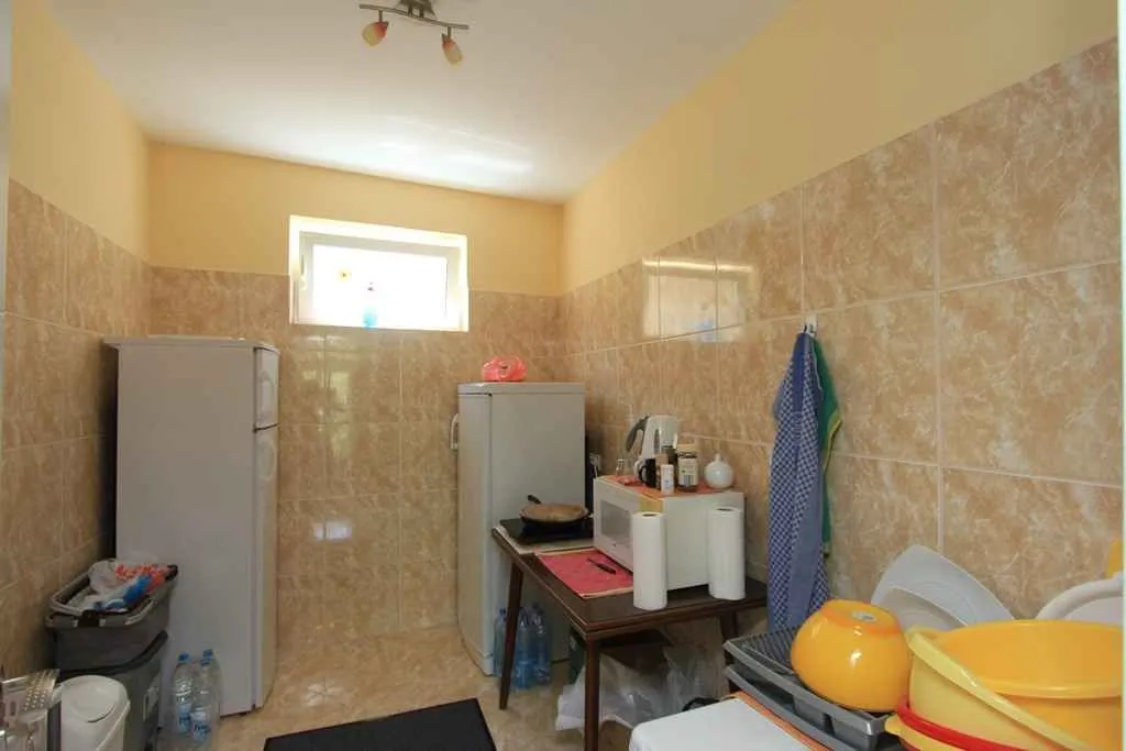 Jednostavna kuhinja sa pločicama na zidovima, dva frižidera i kuhinjskim priborom.