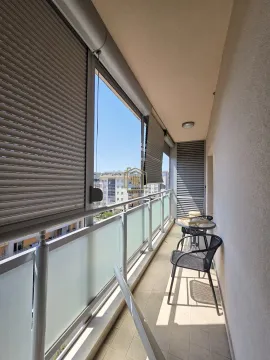 Covered balcony furnished with a glass table and chairs, offering a city view. - image 3