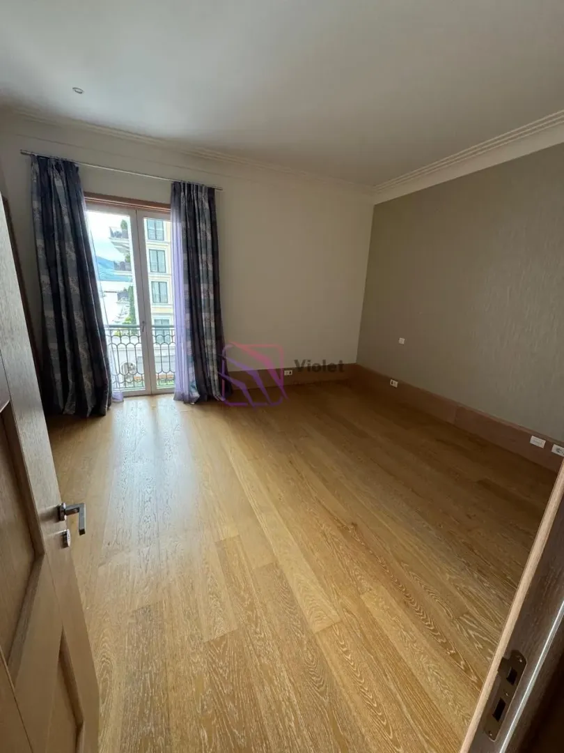 Empty room with wooden flooring and balcony doors.