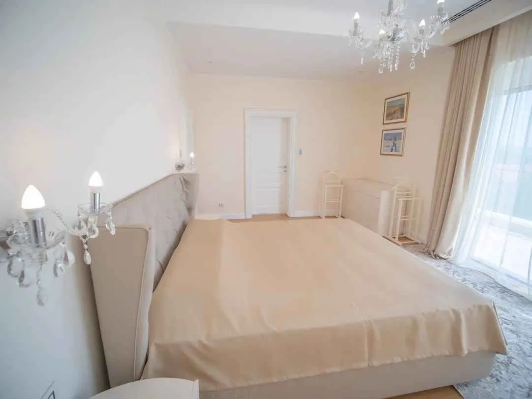 Prostrana spavaća soba sa velikim bračnim krevetom, kristalnim lusterom i izlazom na terasu.