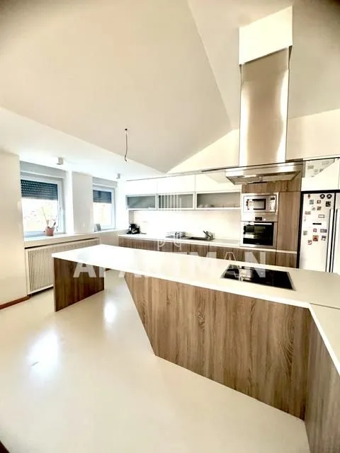 Moderna kuhinja sa velikim šankom i ugrađenim uređajima.