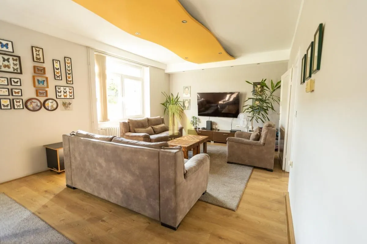 Spacious living room with a sofa set, TV, and decorative wall details.