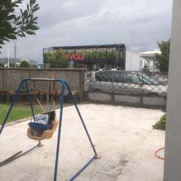 Paved yard with a children's swing and a view of the gate. - image 6