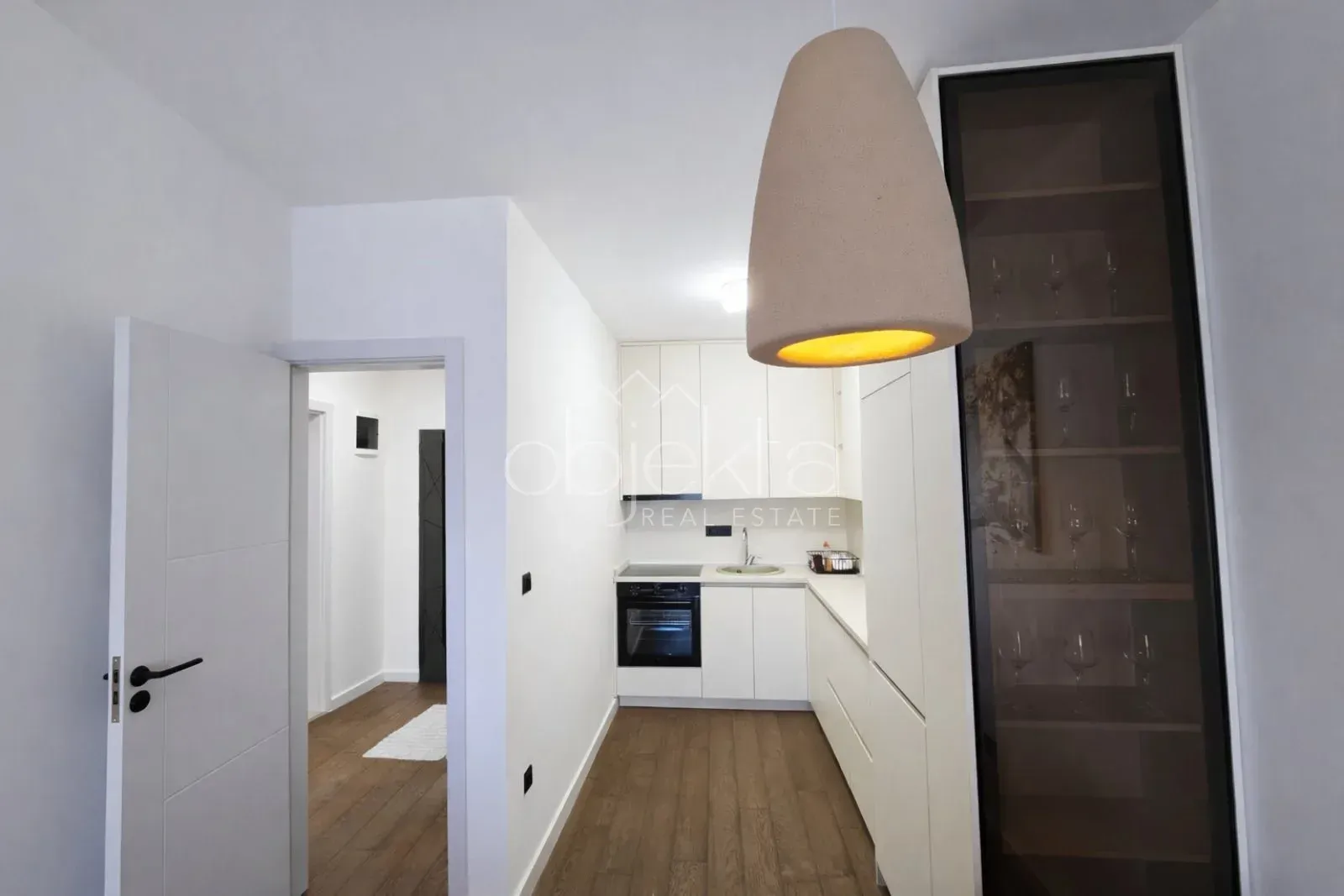 View of a modern kitchen with white cabinets and a built-in oven.