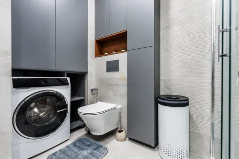 Moderne kupatilo sa ugrađenom mašinom za veš, WC šoljom i sivim elementima. - image 10