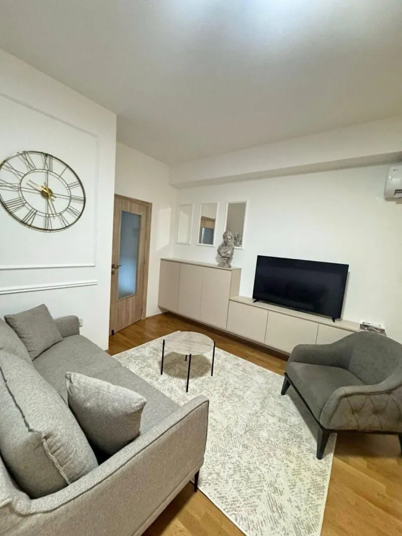 Dnevna soba opremljena garniturom, foteljom i TV komodom.