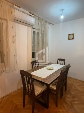 Dining area with a wooden table and chairs, parquet flooring, and curtained windows. - image 2