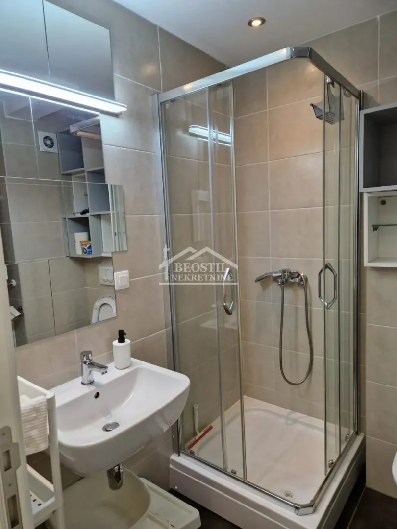 Compact bathroom with a shower cabin, washbasin, and a mirrored cabinet.