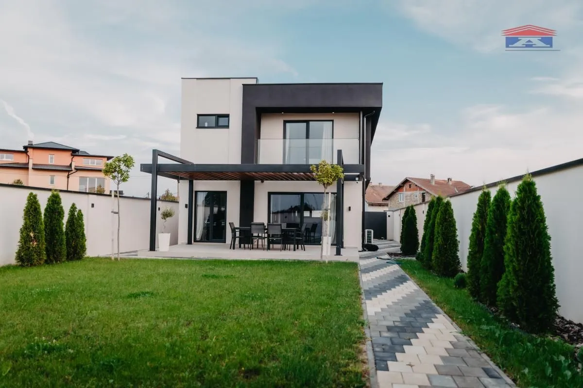 Pogled na zadnju stranu kuće sa uređenim dvorištem i terasom.
