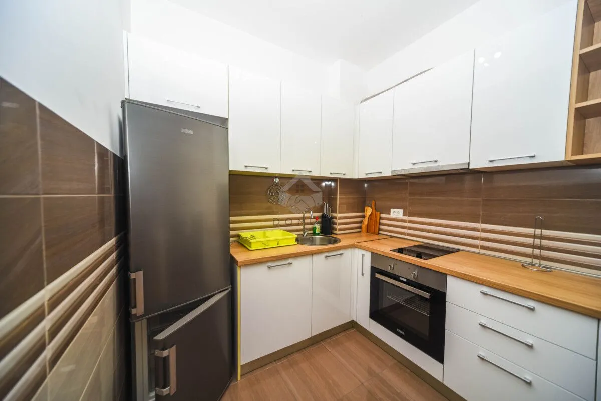 Small kitchen with white cabinets, wooden countertop, and built-in appliances.
